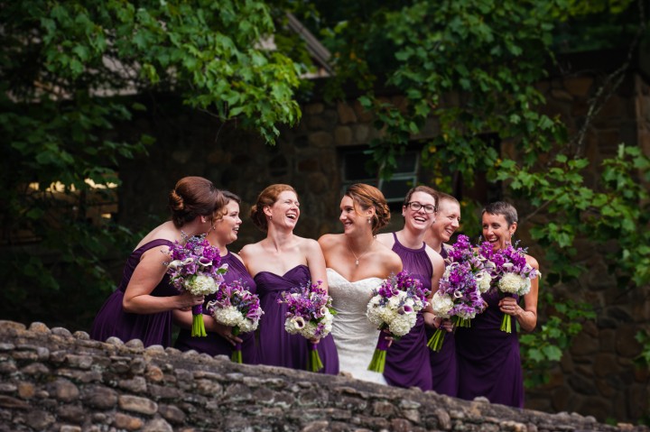 the bride and her ladies in purple bridesmaid dresses on the bridge at Montreat College