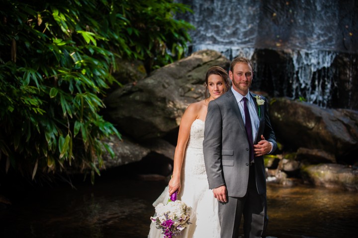 adventurous bride and groom on the rocks in front of a waterfall in the mountains of NC