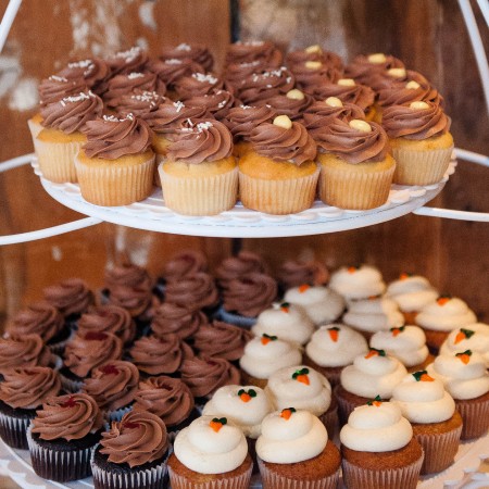 An assortment of cupcakes on a rack at a wedding
