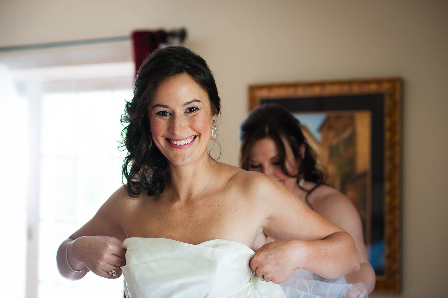 A beautiful bride smiling at her Asheville wedding photographer on her wedding day while getting into her dress