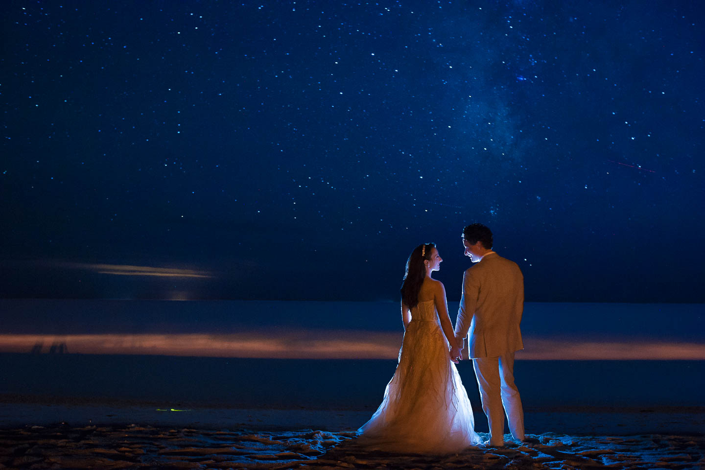 A night image of a couple on the beach after their wedding