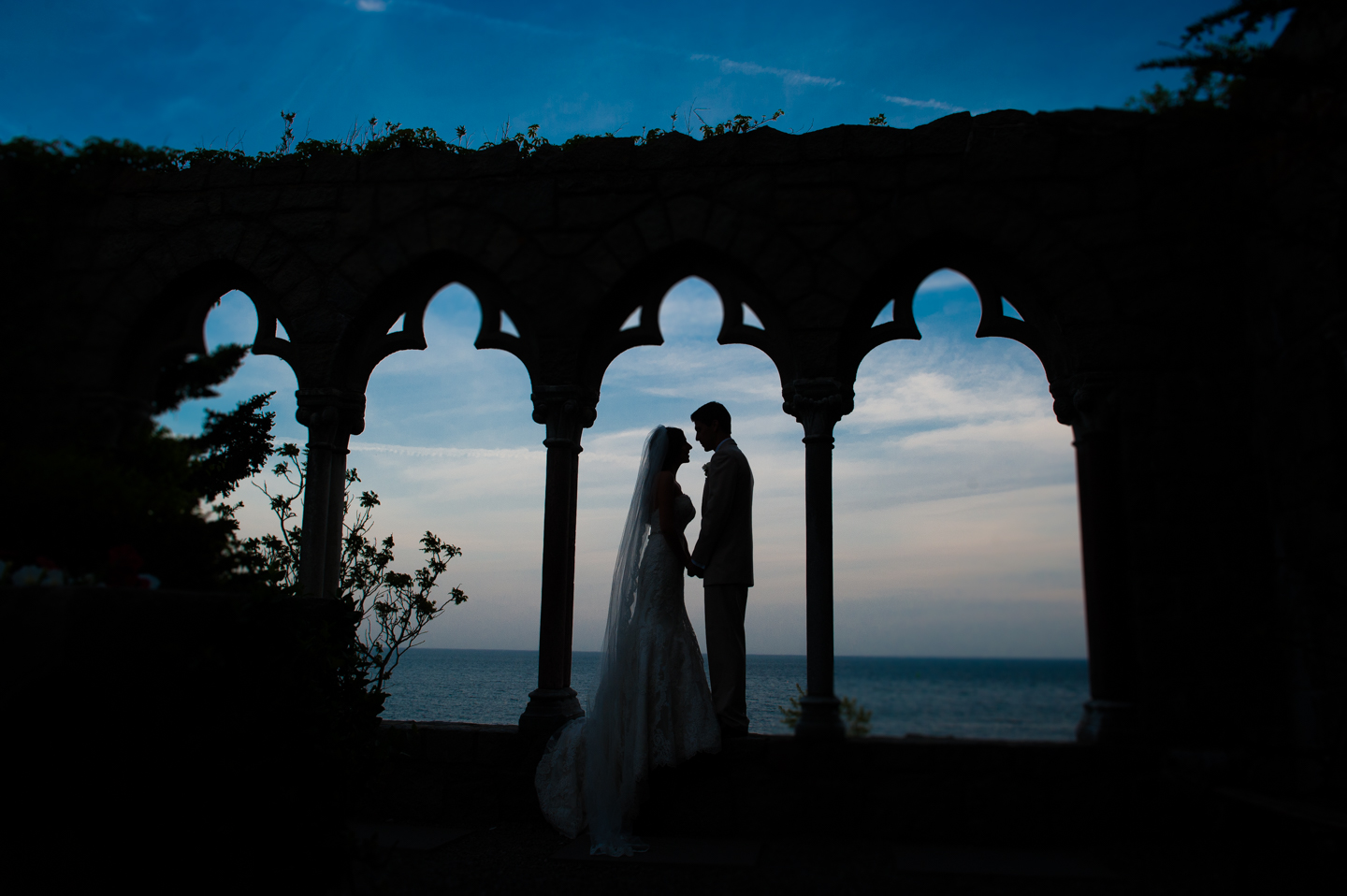 Silhouette of couple in castle arches by the ocean during their wedding