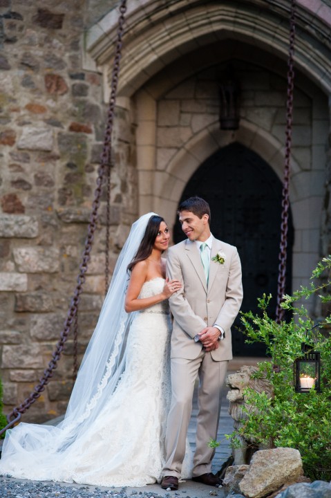 Adorable bride and groom pose looking at each other on castle draw bridge