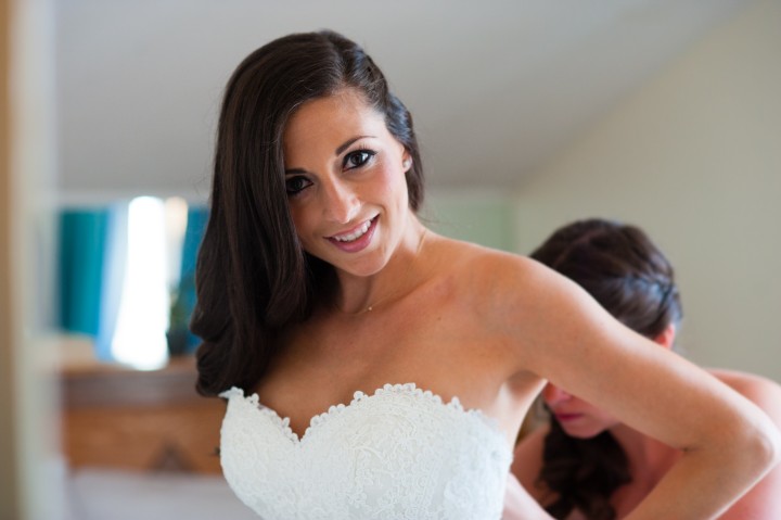 beautiful brides gets zipped into her wedding gown