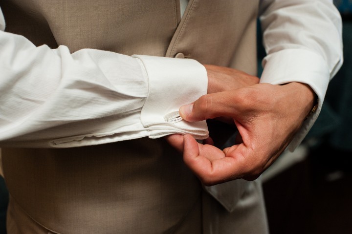 cuff links being put on the groom before his wedding