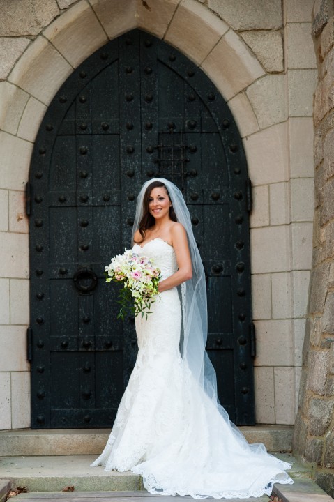 Beautiful bride with her bouquet poses on castle drawbridge