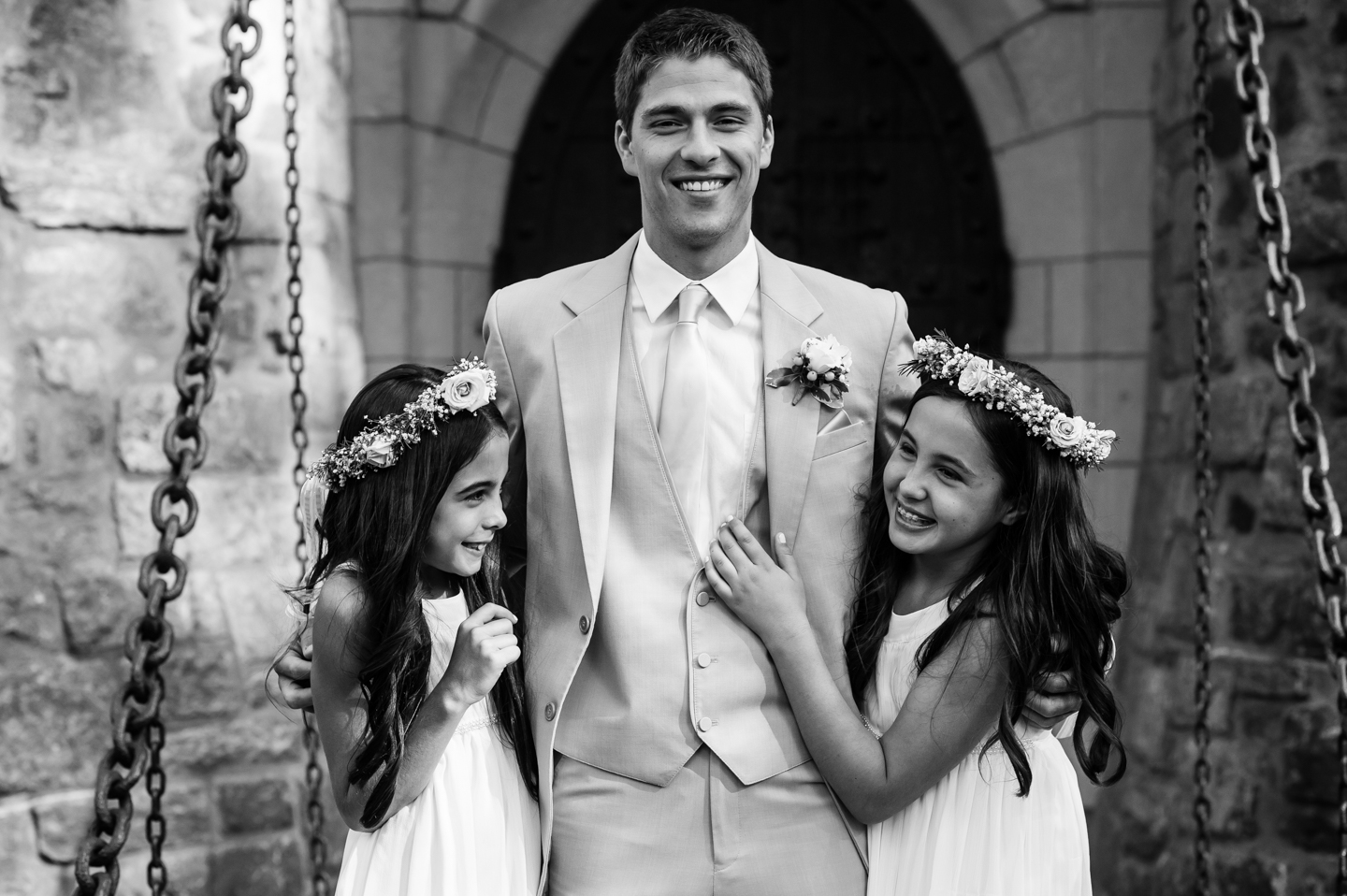 two adorable flower girls pose laughing with the groom