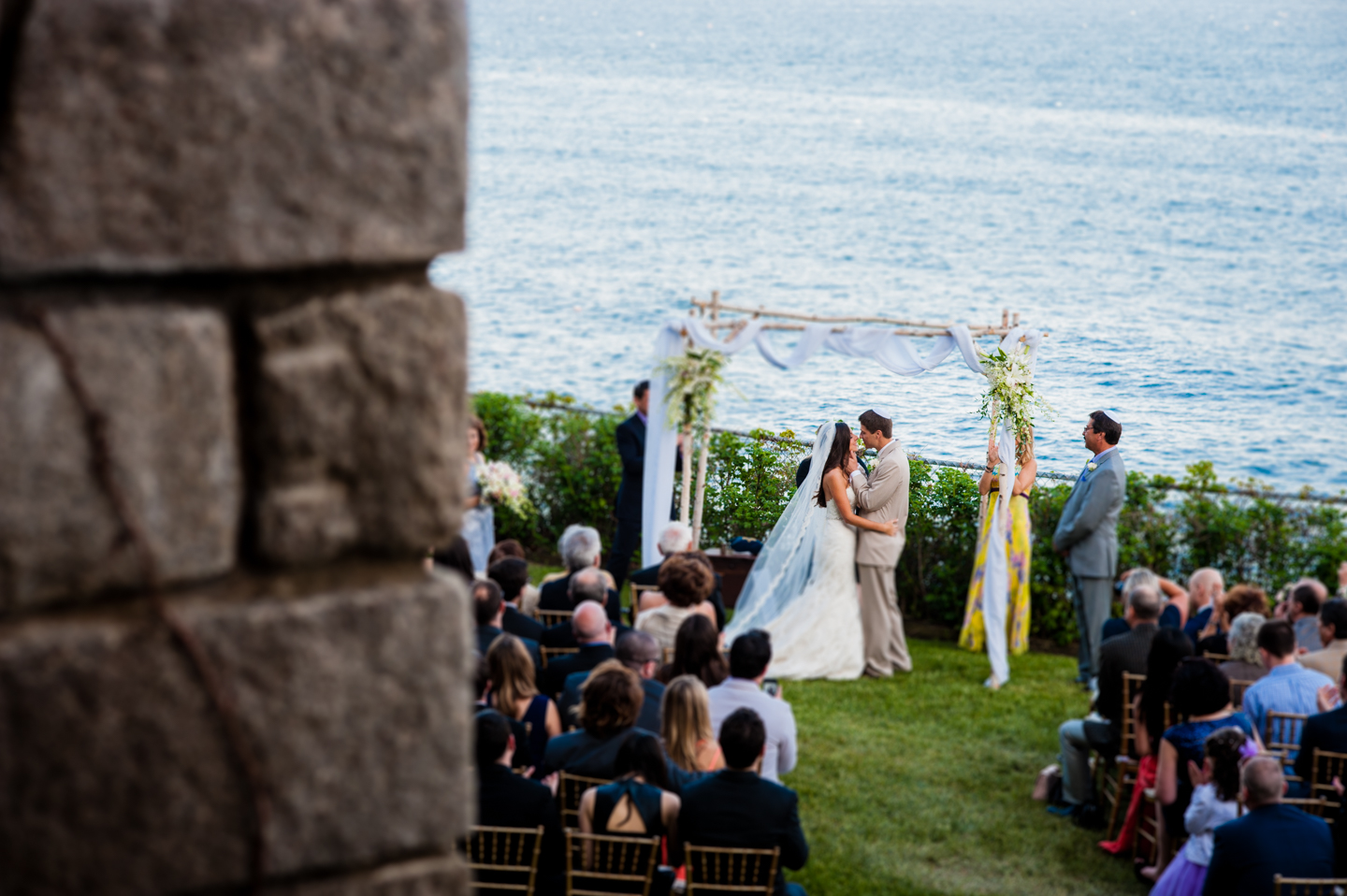 bride and grooms first kiss as husband and wife after their seaside wedding ceremony