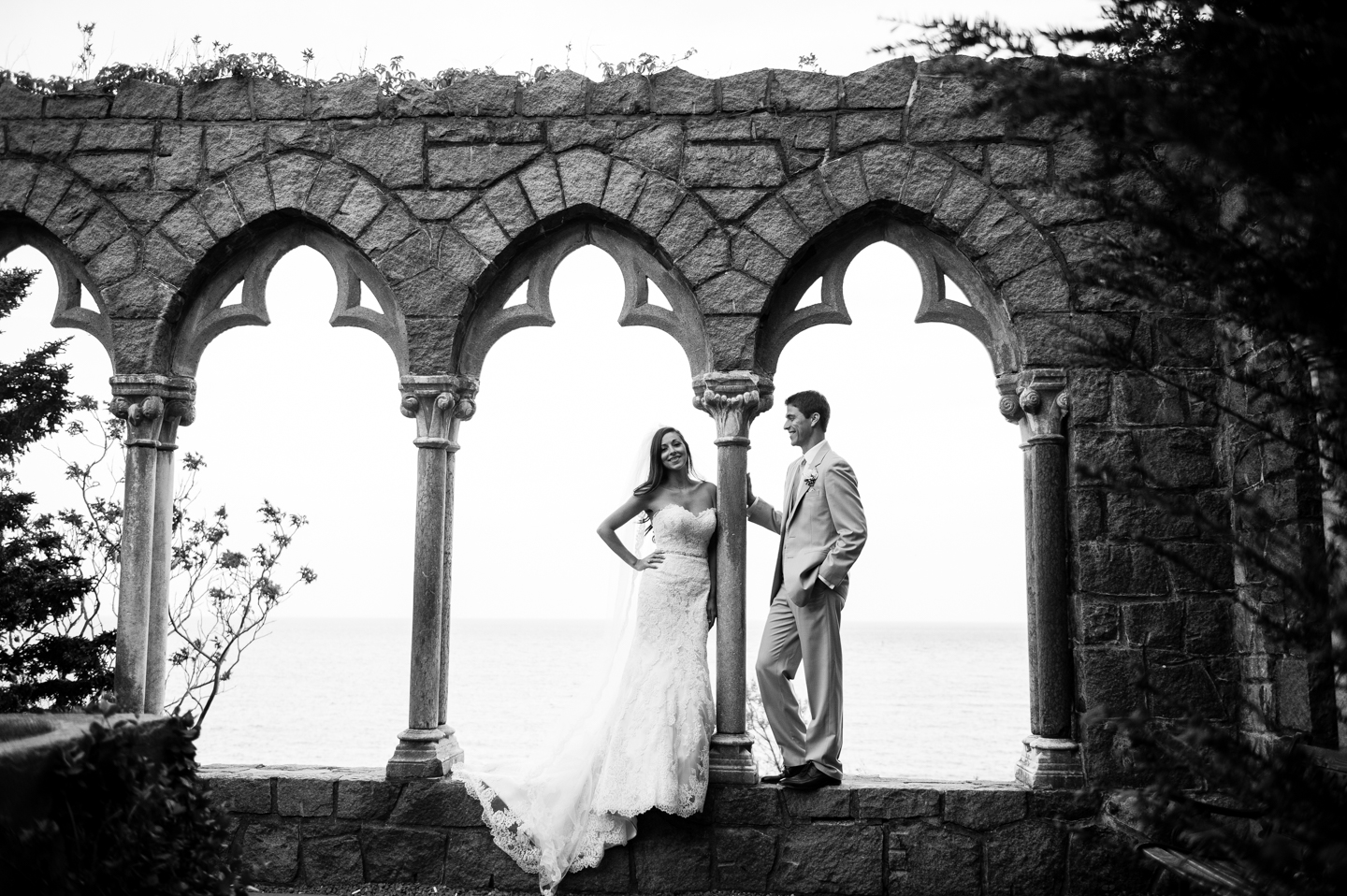 black and white image of bride and groom by the arches at Hammond Castle