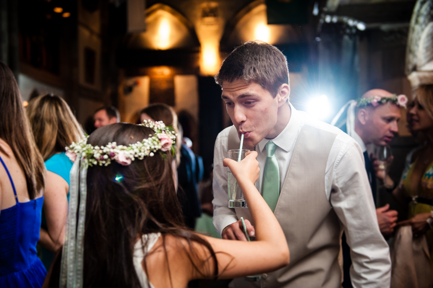 flower girl shares her drink with the groom during wedding reception