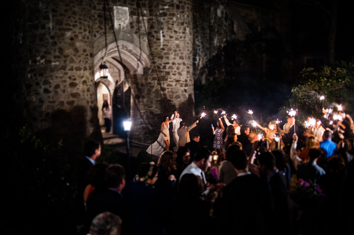 bride and groom run across a castle drawbridge during their sparkler exit 