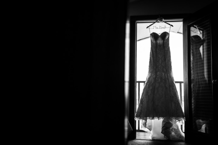 wedding dress hangs  silhouetted in doorway in black and white 