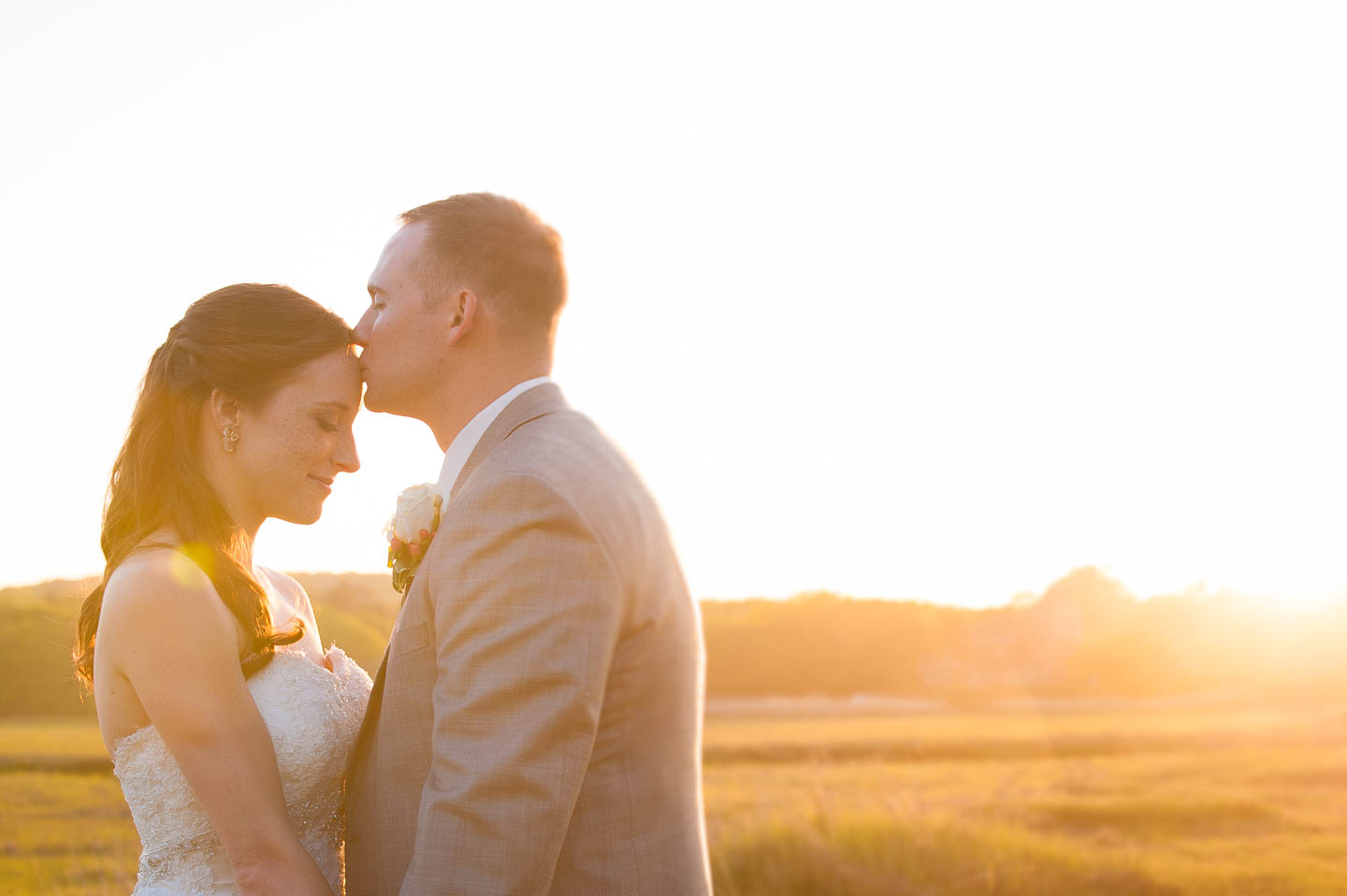 An amazing golden sunset over a marsh behind a couple during there wedding day couples portraits