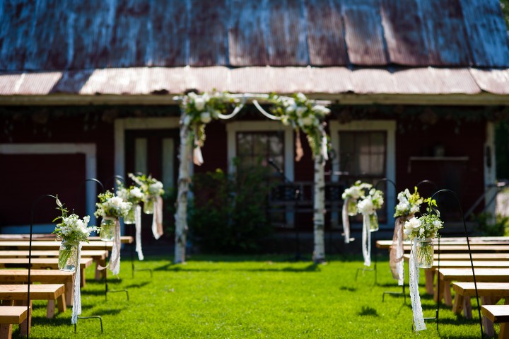 beautiful white flowers in mason jars line the aisle of this elegant outdoor ceremony 