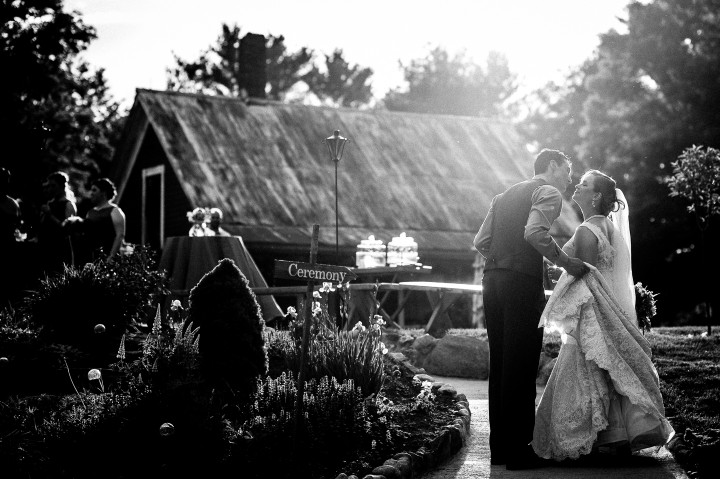 Black and white of Bride and groom kissing at their barn wedding reception 
