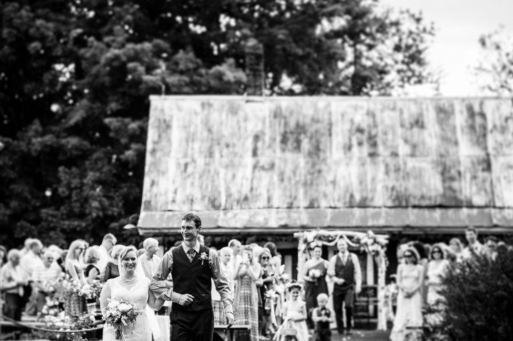 Bride and groom walk down the aisle after their barn wedding ceremony 