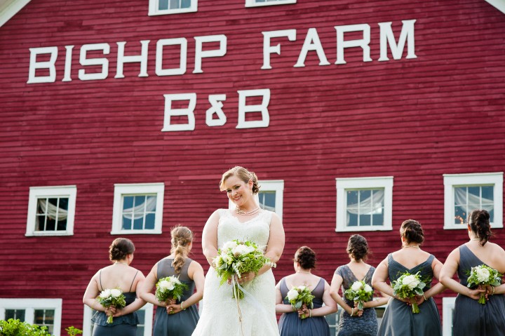 bride smiles at the camera while her bridesmaids show off their beautiful bouquets 