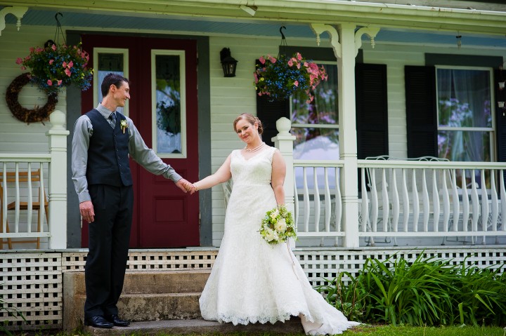 bride and groom hold hands in front of gorgeous old farmhouse 