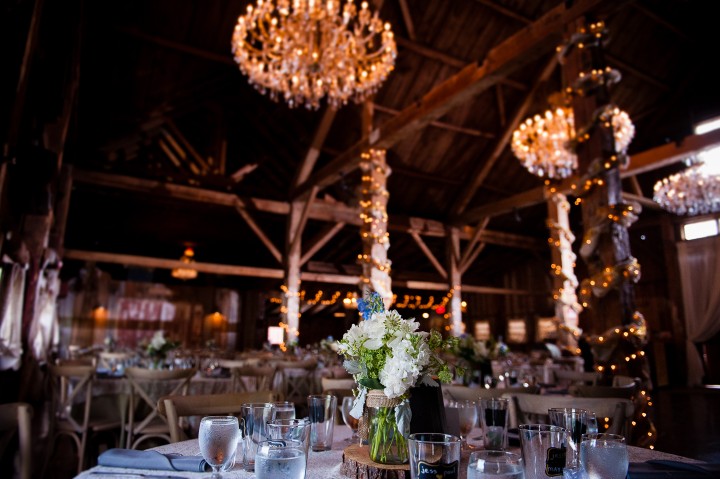 Beautiful purple and green flower centerpieces complimented the rustic wood interior of this barn wedding  