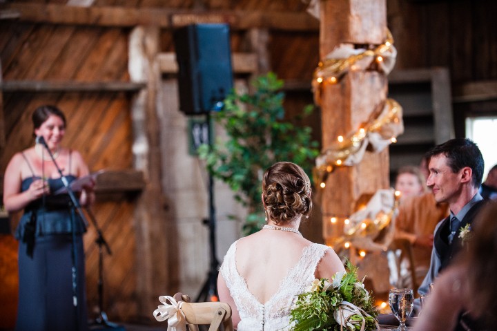 Bride and groom enjoy the toasts during their barn wedding reception 