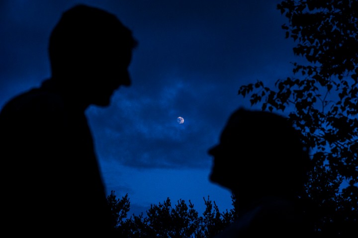 Silhouette of bride and groom with the moon behind them at dusk 