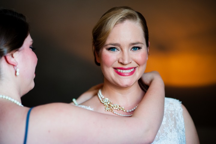 Brides sister helps to put the beautiful brides necklace on her before the ceremony 