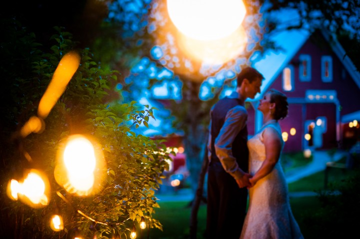 bride and groom kiss with the farm behind them 