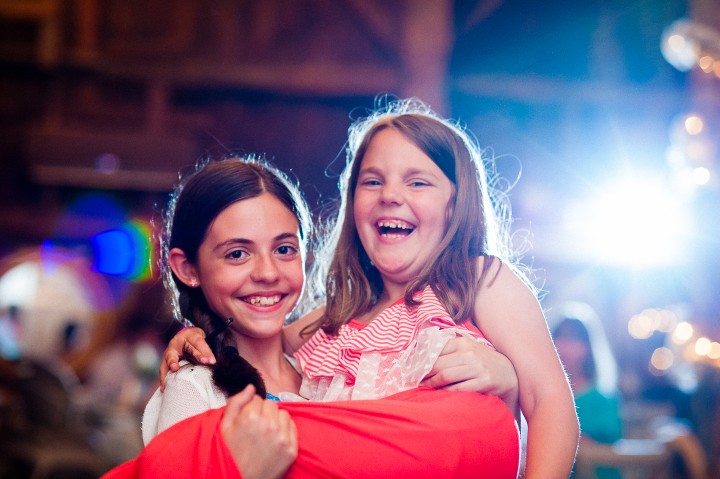 two girls pose for a picture during a barn wedding reception 