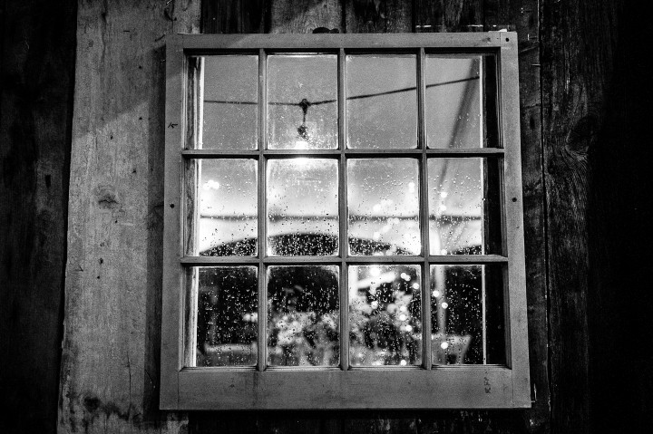 rain coats the windows of the barn during a wedding reception