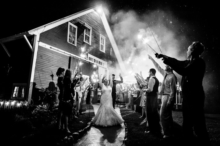 Bride and groom run out of the barn for their sparkler exit at the end of their wedding reception