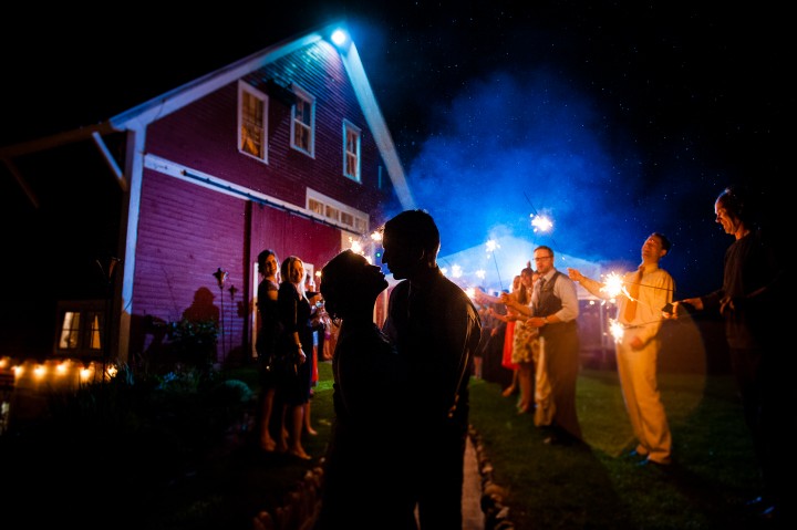 bride and groom kiss with sparklers in the background during their barn wedding reception sparkler exit 