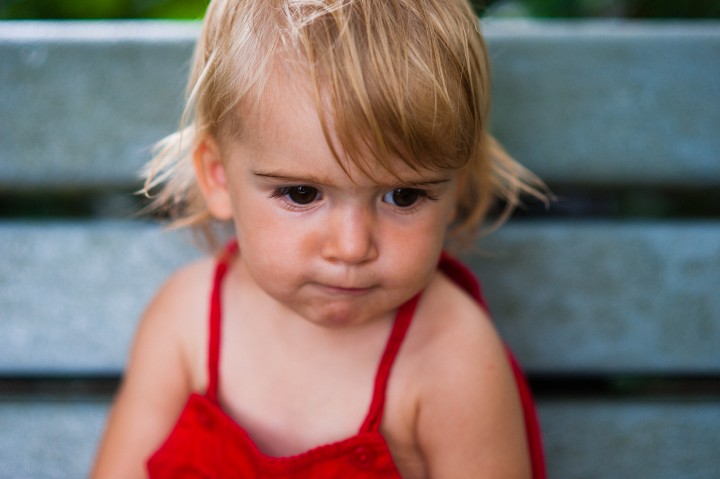 little blonde toddler sits on a park bench during her nc portrait session