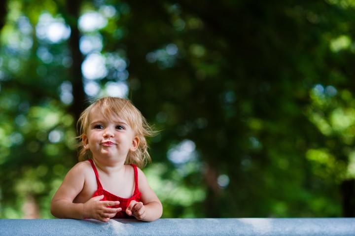 little girl laughs at camera during her woodsy portrait session 