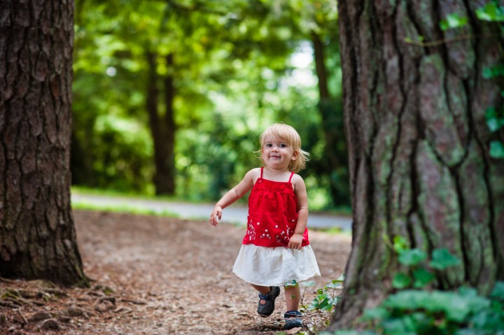 little blonde girl runs down wooded path 