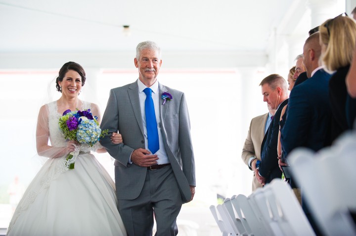 smiling bride and her dad walk down the  aisle during her mountain wedding ceremony 