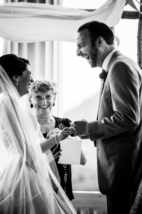 adorable bride and groom laugh while exchanging rings during their beautiful mountain ceremony