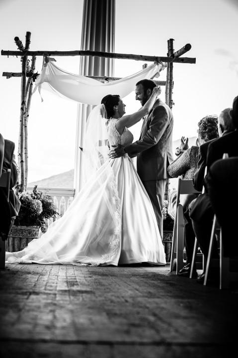 Black and white image of bride and groom smiling at each other just before their first kiss