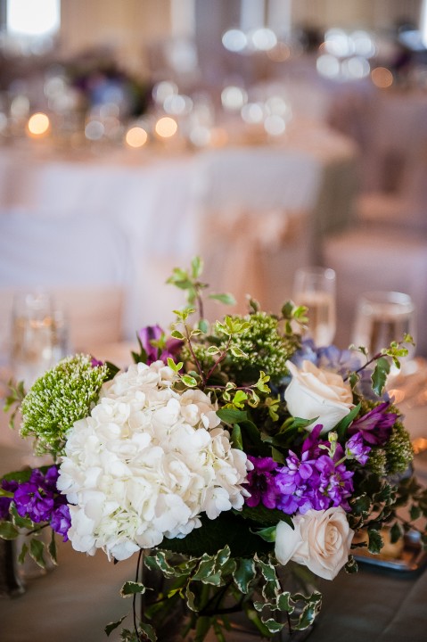 white and purple flowers adorned the circular tables during this summertime wedding reception