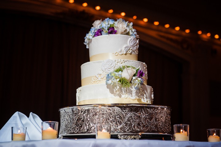 the traditional and very elegant white wedding cake was adorned with pretty purple green and white flowers