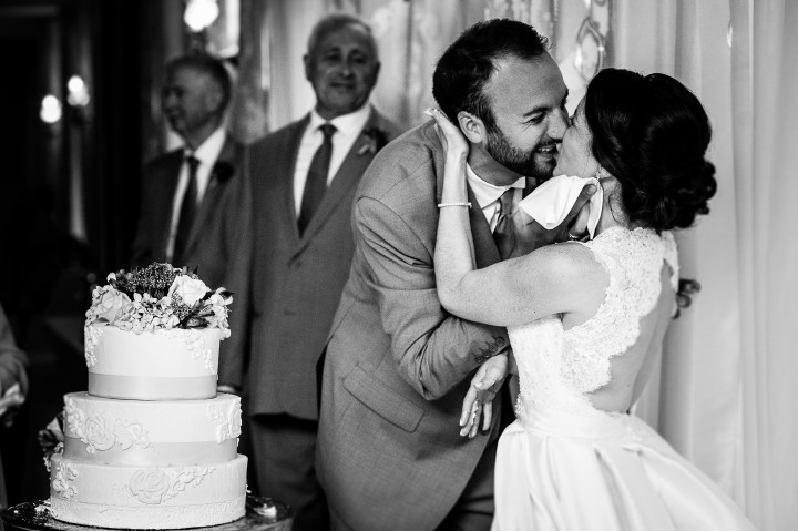 the bride and groom share a post wedding cake cutting kiss during their fun mountain wedding reception