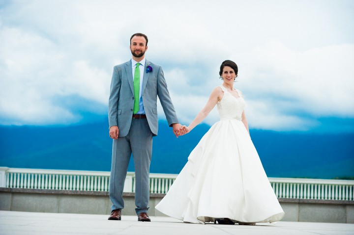 a gorgeous bride and groom hold hands and pose for an outdoor mountain wedding portrait