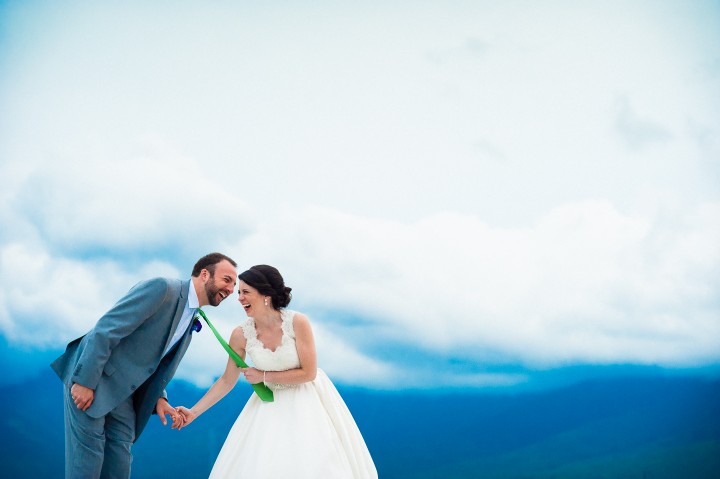 the bride and groom laugh hysterically after the bride grabs grooms tie during couples wedding portraits