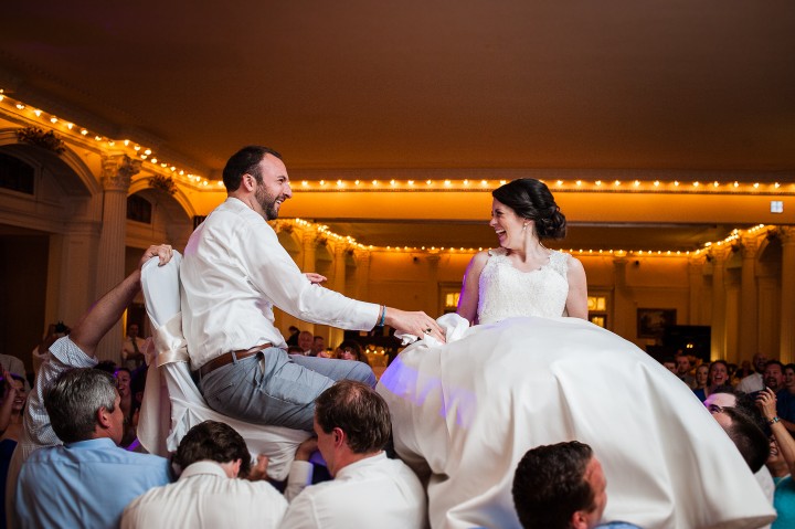 bride and groom laughing at each other during the always fun Hora during their summertime wedding reception