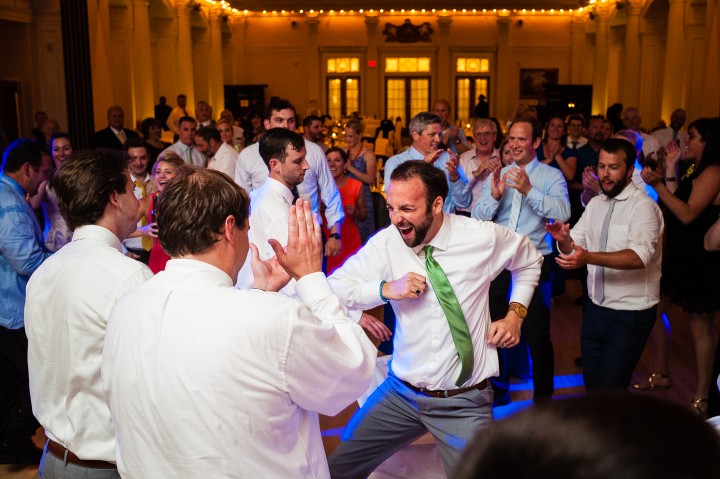 a very happy groom dancing with wedding guests during his fun wedding reception