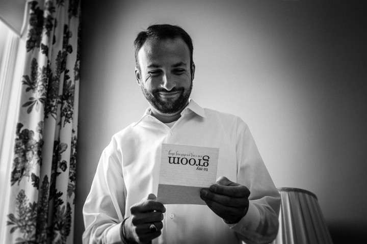 Groom smiling as he opens his wedding day present from his bride to be