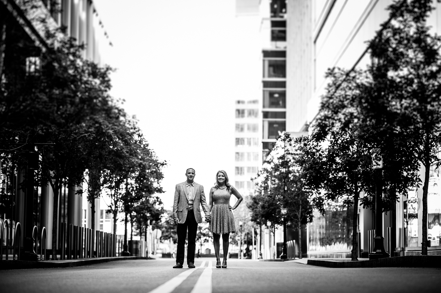 Black and white image of adorable couple standing in treelined street