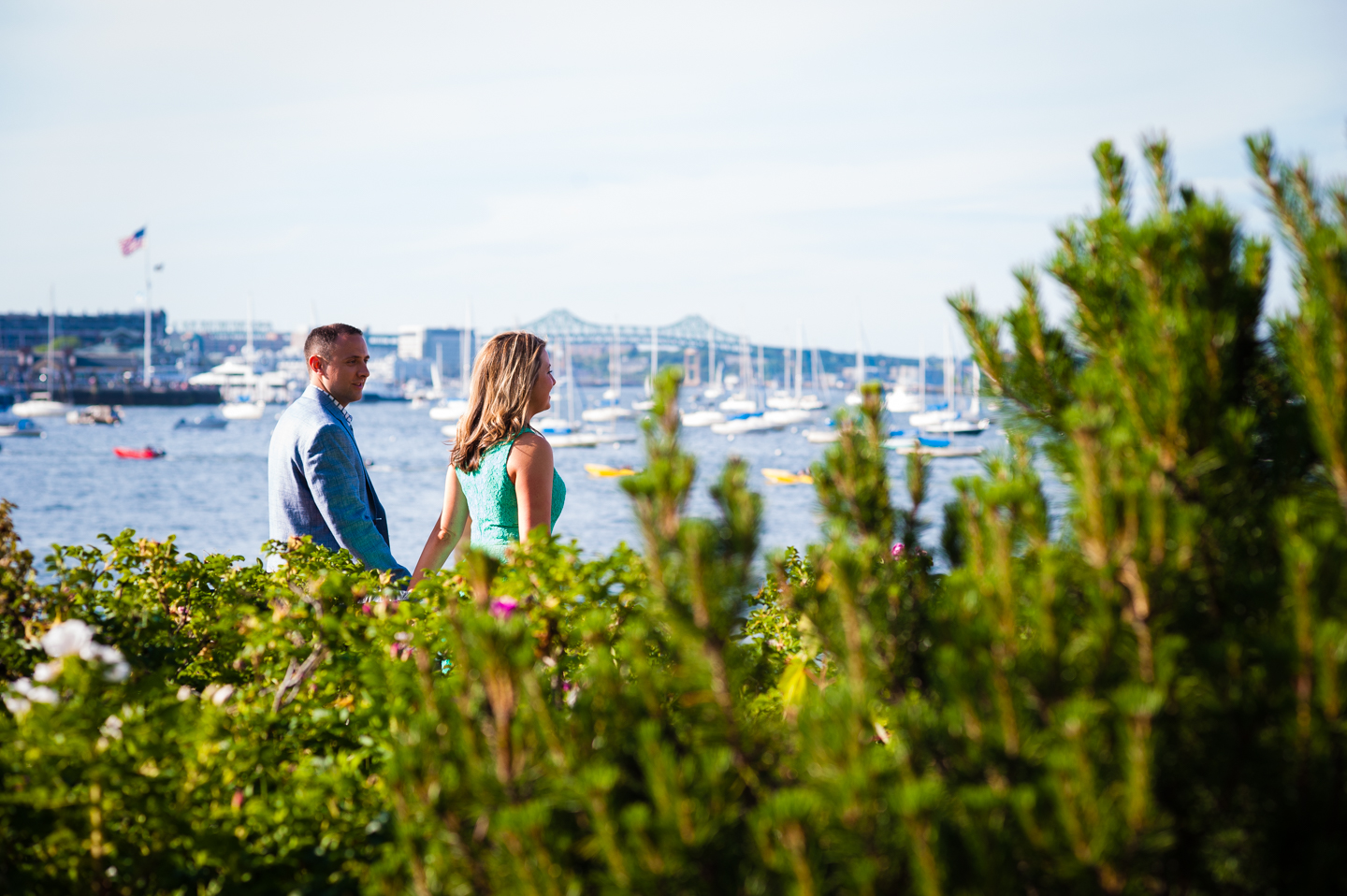 engaged  couples walks by the boston harbor waterfront during their sunset engagement session