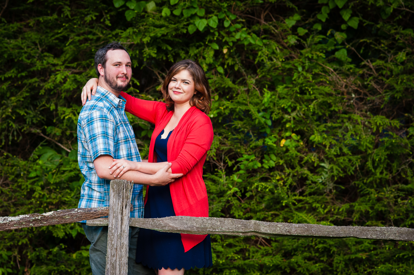 young bride and groom smiling at the camera in front of greenery