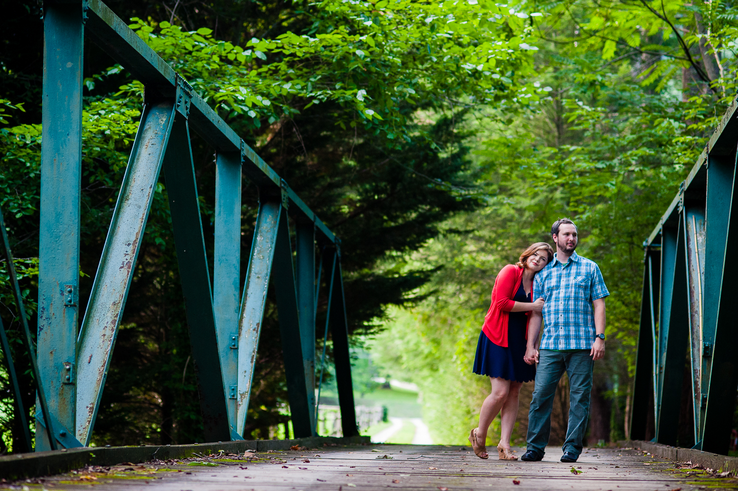 bride and groom pose for a picture on gorgeous wooden bridge in the forest during their backyard wedding 