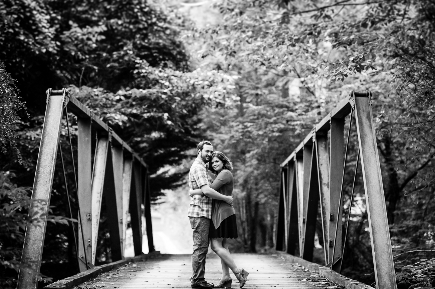 bride and groom embrace in the middle of old wooden forest bridge 